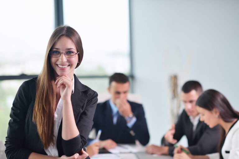 happy young business woman  with her staff,  people group in background at modern bright office indoors